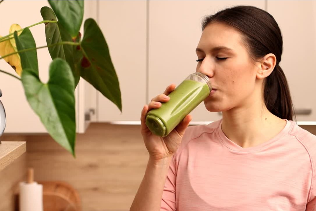 Muškarac pije zeleni smoothie u svetloj kuhinji