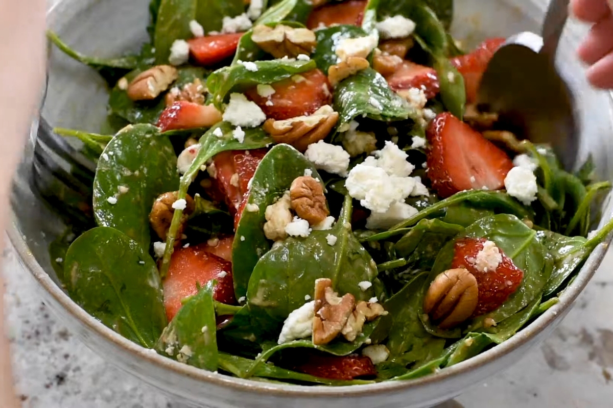 osoba meša salatu sa jagodama i sirom