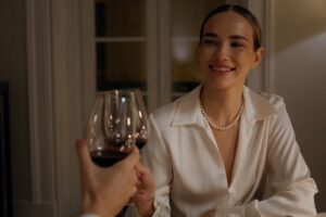 devojka nazdravlja osobi sa čašom vina i smeje se