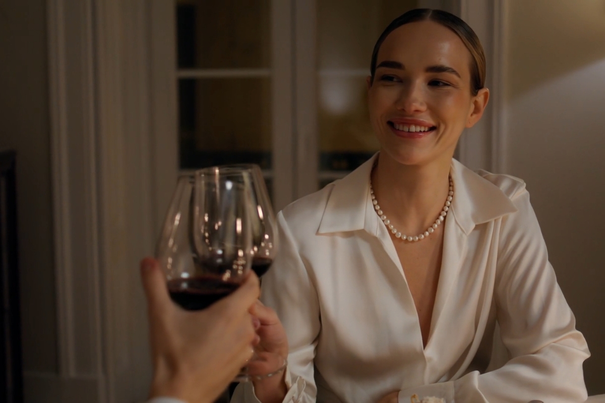 devojka nazdravlja osobi sa čašom vina i smeje se
